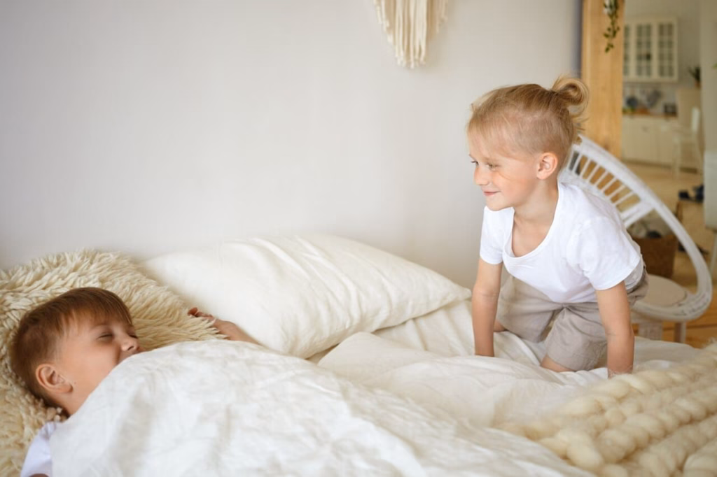 Niño y niña jugando en la cama